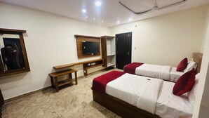 A hotel room with a bed, a desk, a chair, a TV mounted on the wall, and a mirror. - Classic Aditya Grand Inn (Guntur)