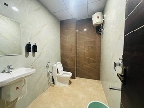 A bathroom with a white sink, a toilet, a shower, and a mirror. - Classic Aditya Grand Inn (Guntur)