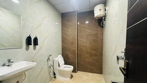 A bathroom with a white sink, a toilet, and a shower. - Classic Aditya Grand Inn (Guntur)