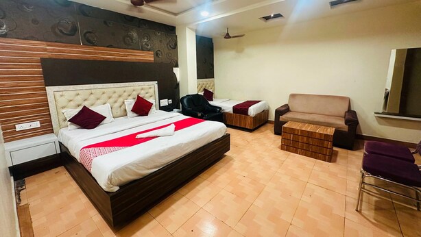 A hotel room with a large bed, a sofa, a chair, and a TV. - Classic Aditya Grand Inn (Guntur)