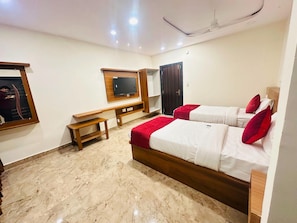 A hotel room with a bed, a desk, a television, and a ceiling fan. - Classic Aditya Grand Inn (Guntur)