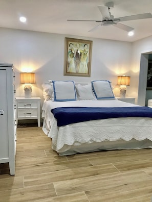 Ein Schlafzimmer mit einem Bett, Nachttischen, einem Deckenventilator und einem Bild an der Wand.