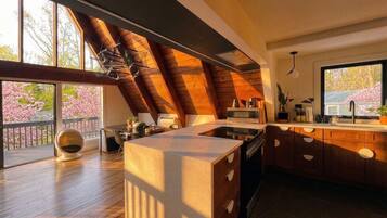 A modern kitchen with a large island, wooden ceiling, and a view of cherry blossoms.