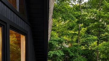 A deck with two modern chairs and a glass door leading to a room.