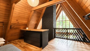 Un dormitorio estilo ático con cama tipo litera, un escritorio pequeño y un ventanal grande.