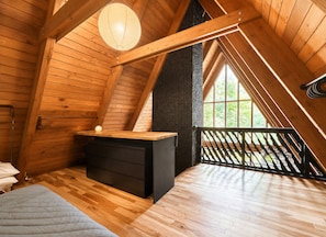 A wooden attic bedroom with a loft bed, a small desk, and a large window. - Custom A-Frame | Lake Access • Fire Pit (Highland Lakes)
