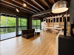A spacious room with a large window, a sofa, a desk, and a chair. - Custom A-Frame | Lake Access • Fire Pit (Highland Lakes)