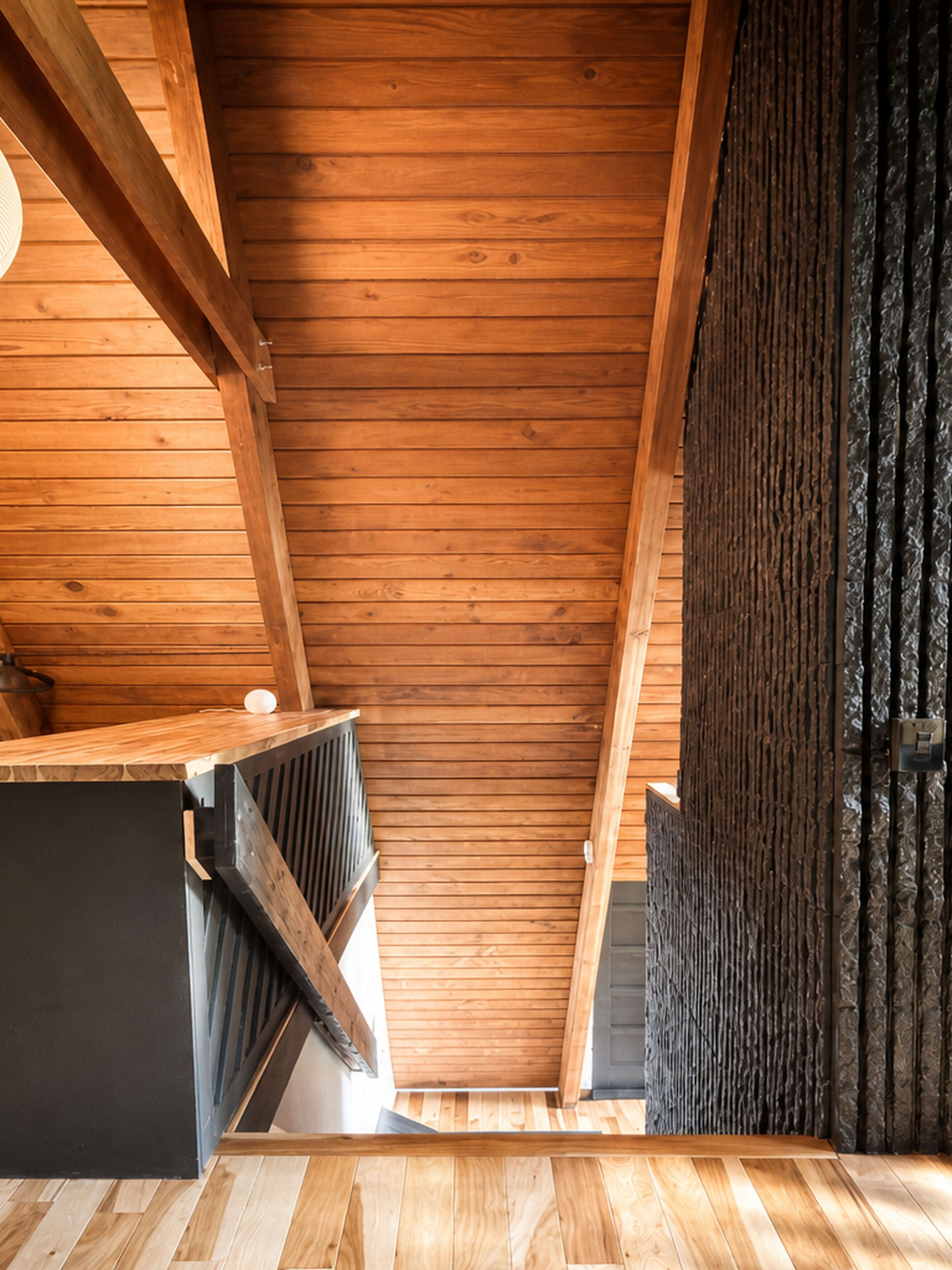 A wooden interior with a sloped ceiling, a radiator, and a dark curtain.