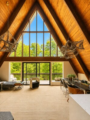 Un espacio amplio en el ático, con techo alto, ventanas grandes y vistas a árboles.