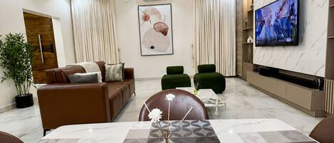 A modern living room with a sofa, chairs, a coffee table, and a TV mounted on the wall.
