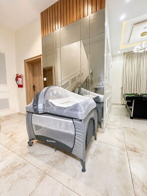 A modern hotel room with a large mirror, a bed with a protective cover, a pool table, and a fire extinguisher. - Spacious Luxury 5-Bedroom Villa in Osapa Lekki With Free Parking (Lekki)