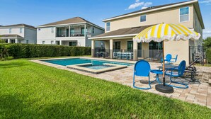 Ein Wohnhaus mit Swimmingpool, Sitzgelegenheiten im Freien und einem großen Sonnenschirm.