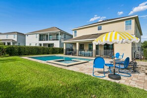 A residential property with a swimming pool, outdoor seating, and a large umbrella. - PacMan, Foosball, Shuffleboard, Large Backyard, Chef Kitchen: Metropolis Estate (Kissimmee)