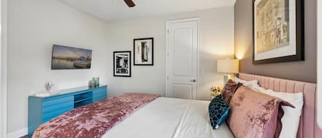 Un dormitorio con cama, ventilador de techo, cómoda y puerta.