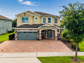 A two-story house with a garage, a front porch, and a well-maintained lawn. - PacMan, Foosball, Shuffleboard, Large Backyard, Chef Kitchen: Metropolis Estate (Kissimmee)