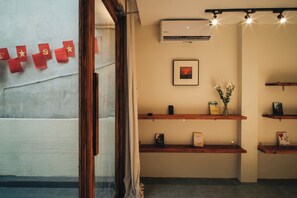 A room with a wooden shelf, an air conditioning unit, and a framed picture on the wall. - Late Autumn - 3BR private house in vibrant Hanoi - Free airport transport (Hà Nội)