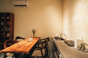 A wooden dining table with chairs, a small vase with flowers, and a kitchen counter with a sink and various items. - Late Autumn - 3BR private house in vibrant Hanoi - Free airport transport (Hà Nội)