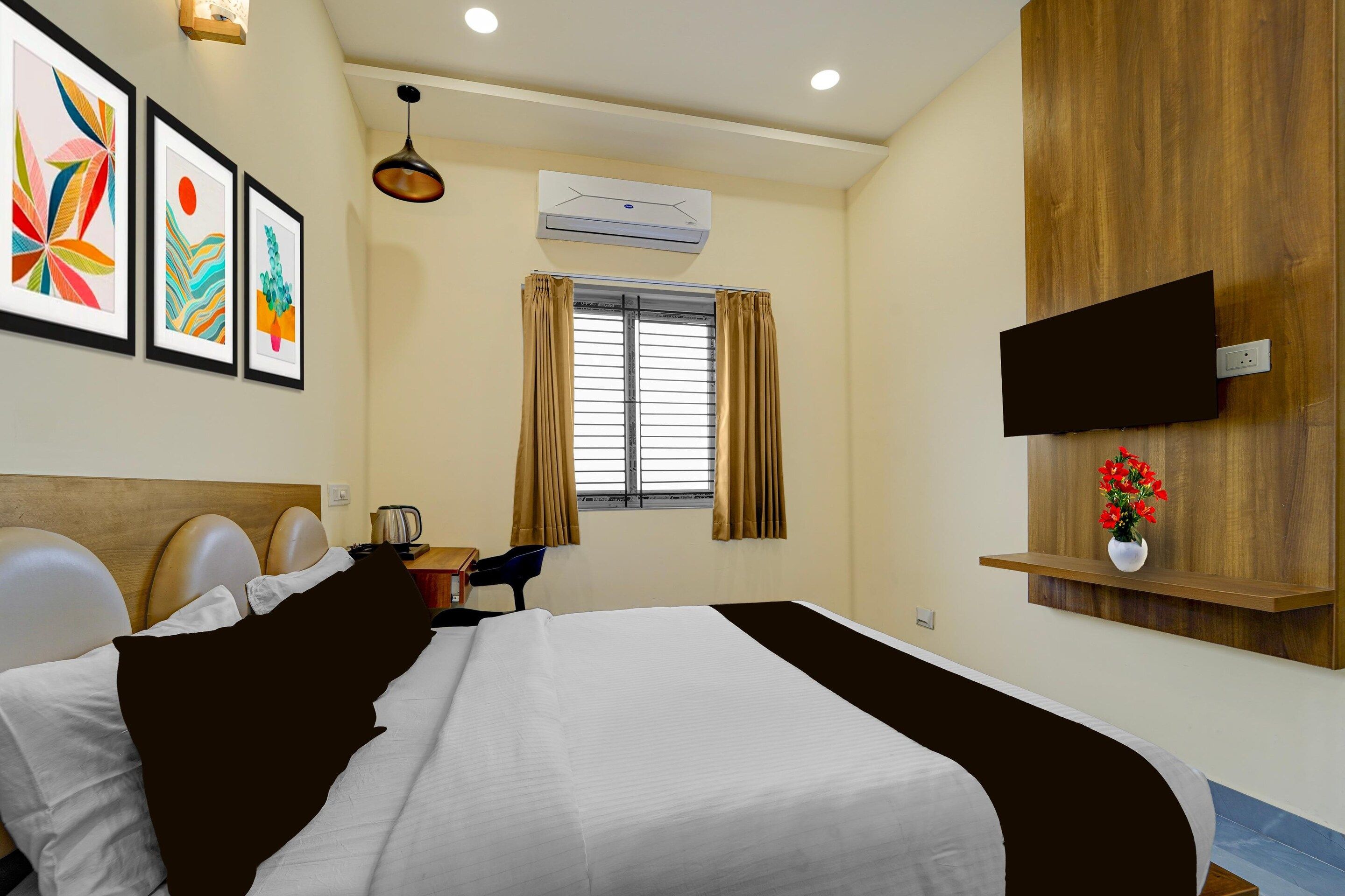Une chambre d’hôtel comprenant un lit, un bureau, une chaise, un téléviseur fixé au mur et une fenêtre avec des rideaux.