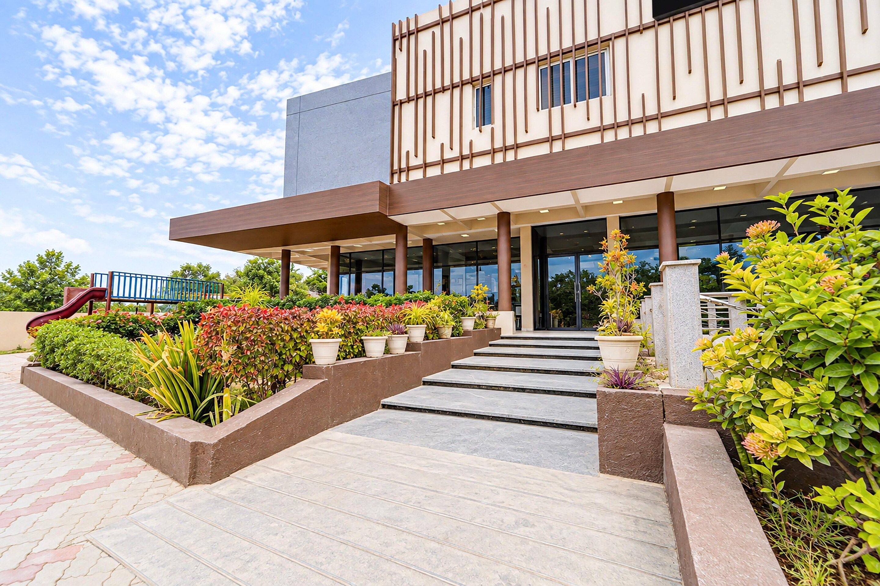 A modern building with a flat roof, large windows, and a central entrance with steps leading up to it.