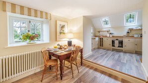 Een eetruimte met een gedekte tafel voor het ontbijt, een radiator en een raam met uitzicht op bomen.