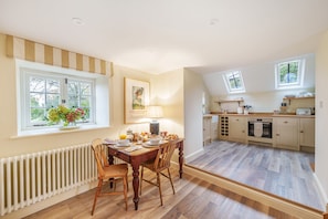 A dining area with a table set for breakfast, a radiator, and a window with a view of trees. - Puddle Cottage  -  Chebbard, Dorchester (Chebbard)