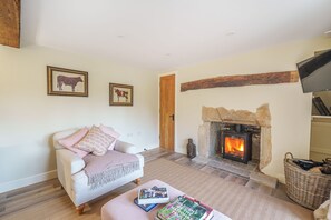 A cozy living room with a fireplace, a sofa, and two framed animal paintings on the wall. - Puddle Cottage  -  Chebbard, Dorchester (Chebbard)