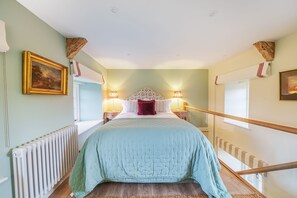 Ein Schlafzimmer mit einem Bett, zwei Nachttischlampen, einem Heizkörper, einem Fenster und einem Bild an der Wand.
