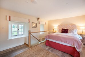 Ein Schlafzimmer mit einem Bett, einem Fenster, einer Holzreling und einem Nachttisch mit einer Lampe.