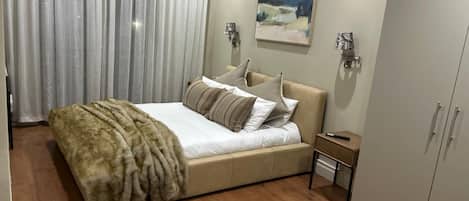 A bedroom with a bed, a nightstand, a wardrobe, and a painting on the wall.
