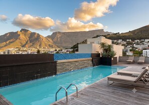 Ein Pool auf dem Dach mit Blick auf einen Berg und eine Stadtansicht.