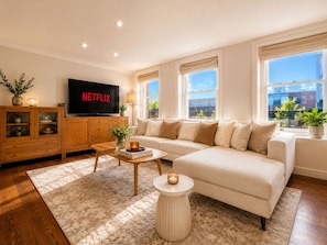 Ein modernes Wohnzimmer mit einer Couch, einem Couchtisch und einem Fernseher, der 'NETFLIX' zeigt.