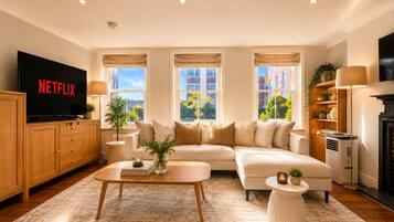 A modern living room with a sofa, coffee table, and a flat-screen TV displaying 'NETFLIX'.