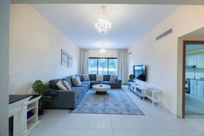 A modern living room with a grey sectional sofa, a round coffee table, and a TV mounted on the wall.