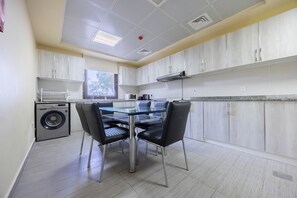 A modern kitchen with a dining area, featuring stainless steel appliances, a built-in microwave, and a window with a view of trees.