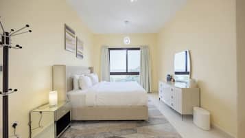 A modern bedroom with a bed, bedside table, lamp, and a dresser.