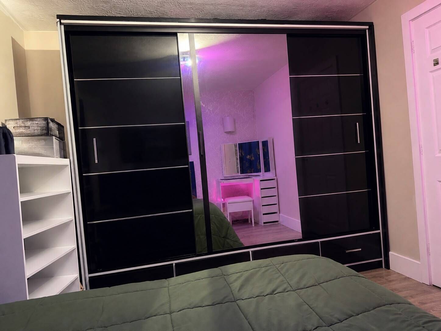 Un dormitorio con cama, armario y espejo.