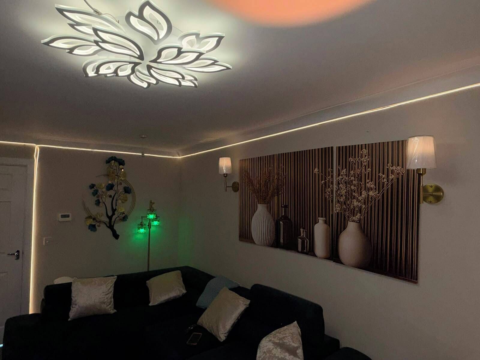 A modern living room with a black sofa, decorative wall art, and a ceiling light fixture.