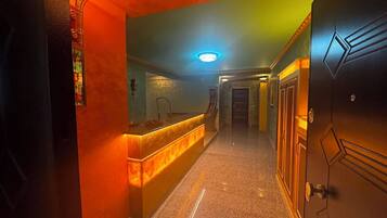 A hotel hallway with a reception desk, a mirror, a door, and a light fixture.