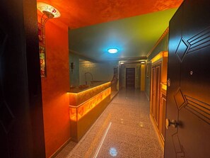 A hotel hallway with a reception desk, a mirror, a door, and a light fixture. - Luxury Apartament with an amazing seaview (Golem)