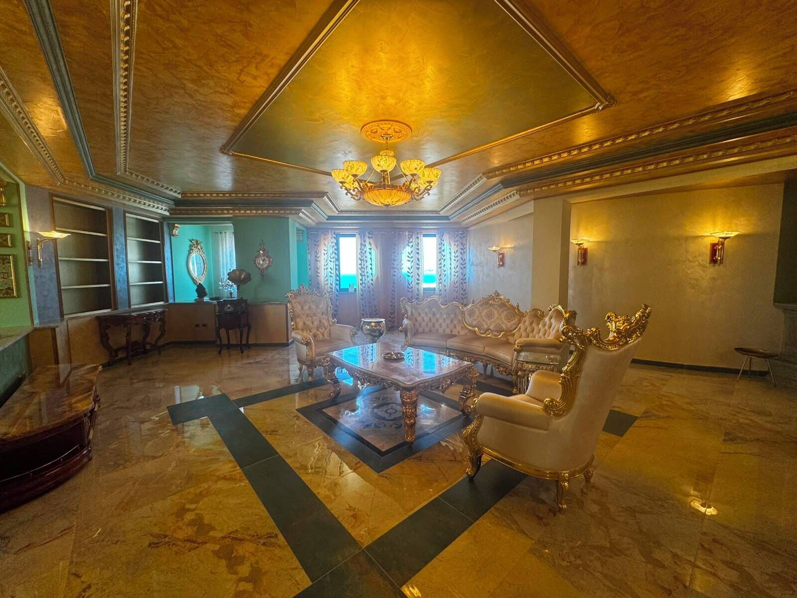 A luxurious lobby with a grand chandelier, ornate furniture, and a marble floor.