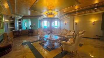 A luxurious lobby with a grand chandelier, ornate furniture, and a marble floor.