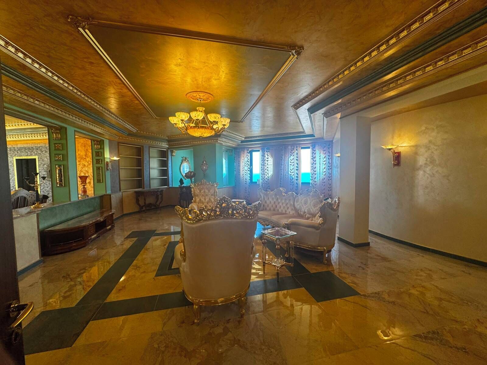 A luxurious lobby with ornate furniture, a grand chandelier, and a marble floor.