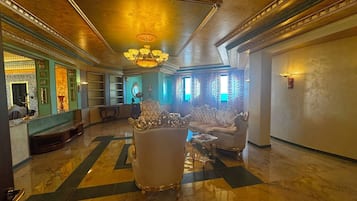A luxurious lobby with ornate furniture, a grand chandelier, and a marble floor.