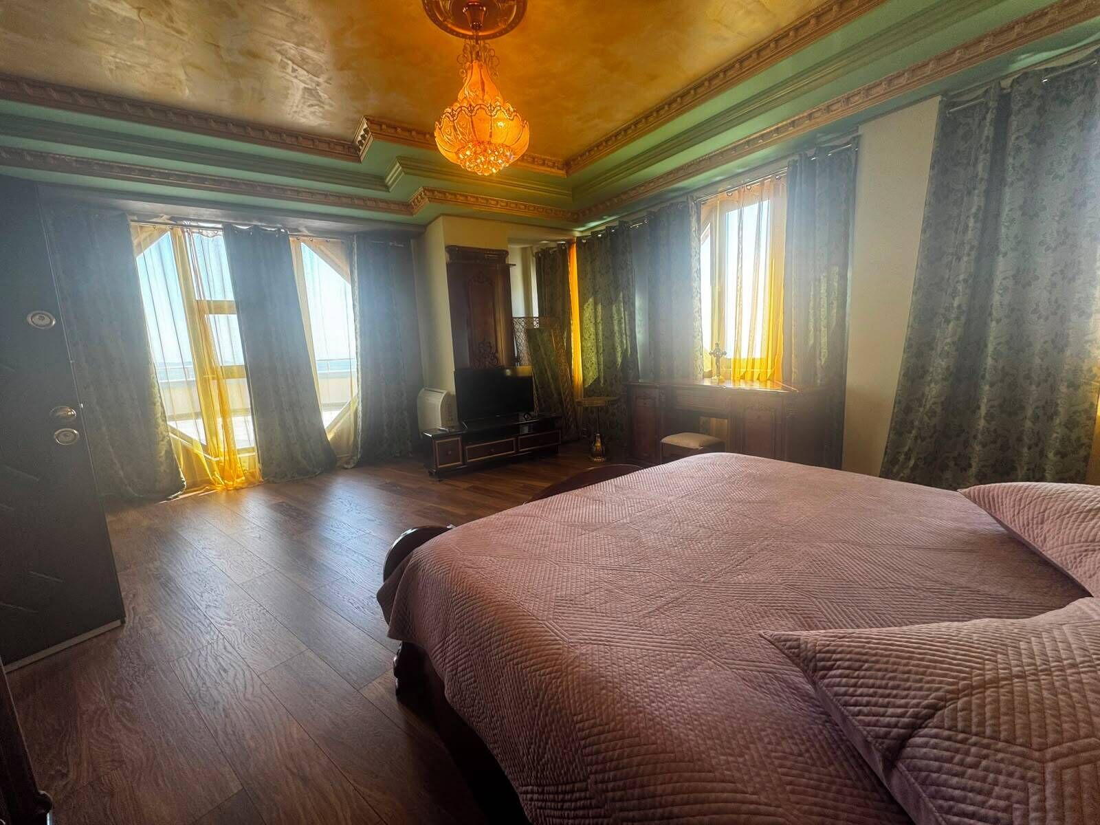 A bedroom with a large bed, a television, and a chandelier.