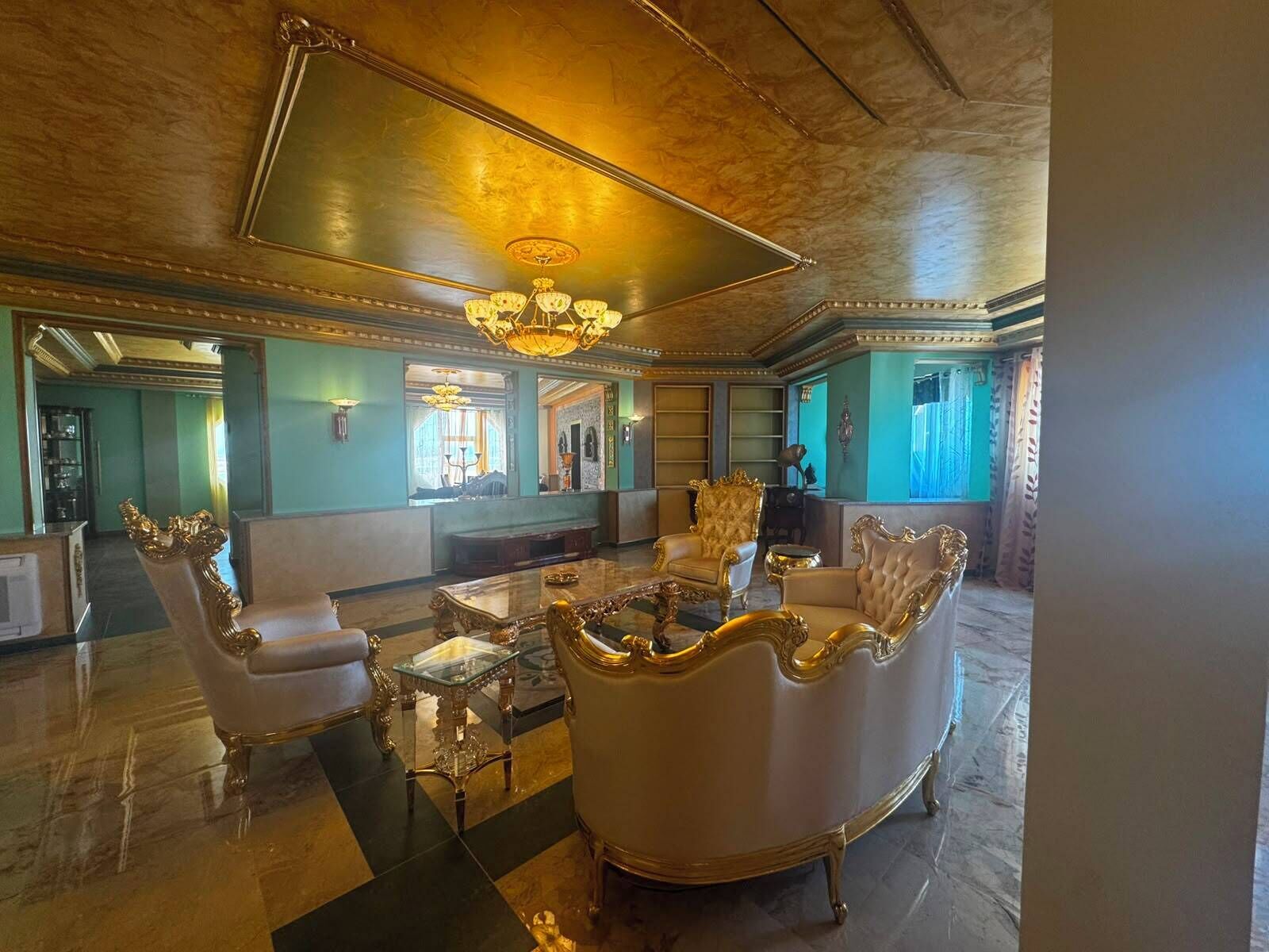 A luxurious lobby with ornate furniture, a grand chandelier, and a large mirror.