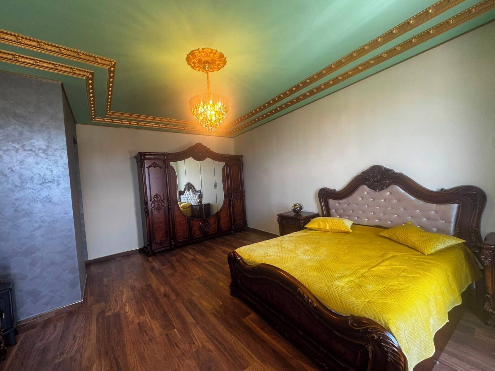 A bedroom with a wooden bed, a mirror cabinet, and a chandelier.