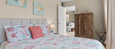 A bedroom with a bed, a wooden wardrobe, and a door leading to another room.