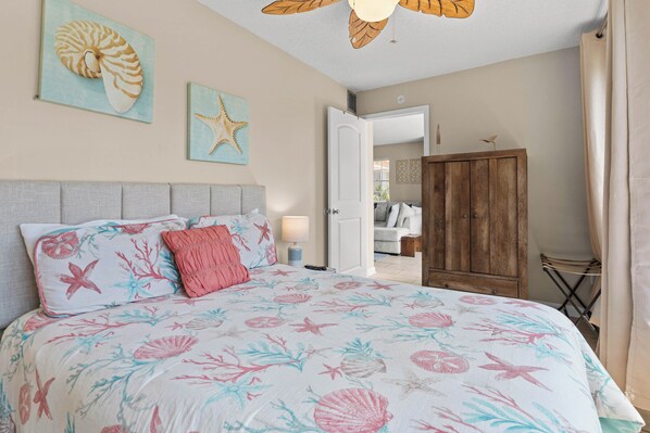 A bedroom with a bed, a wooden wardrobe, and a door leading to another room.