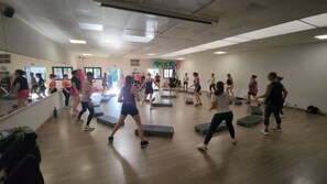 A group of people exercising in a room with wooden floors and mirrors on the walls.