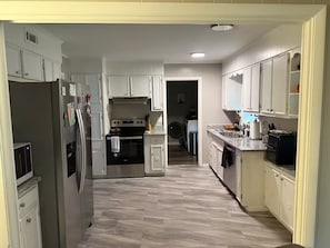 A kitchen with white cabinets, a stainless steel refrigerator, a stove, and a microwave. - Hillwood Circle home with fast EV charger (Augusta)